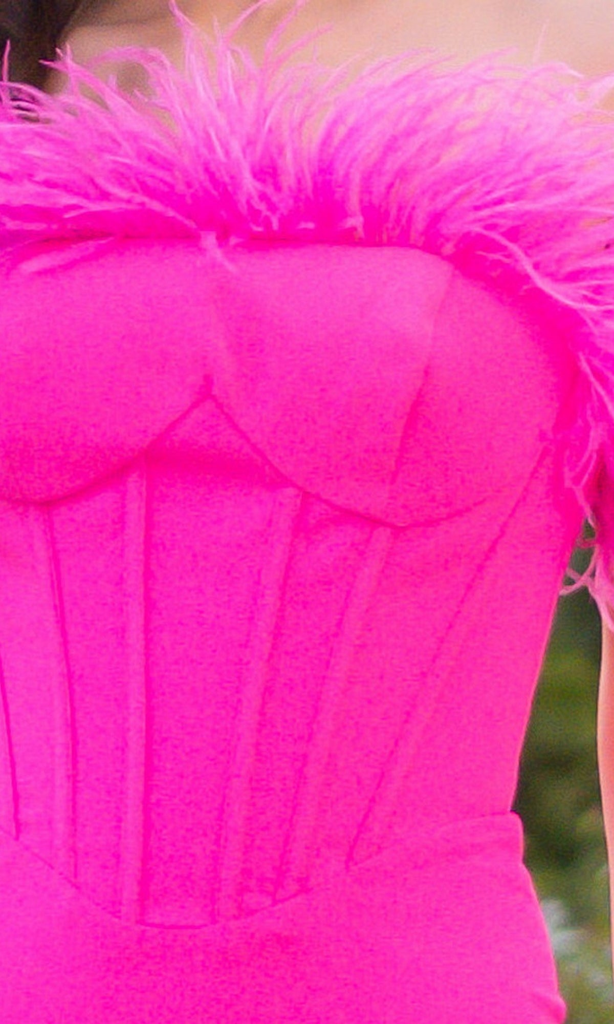 Close-up of a person wearing the Velvi Feathered Strapless Long Prom Dress Sloane in bright pink, featuring lace-up back, feather trim at the top, and visible seam lines on the bodice.